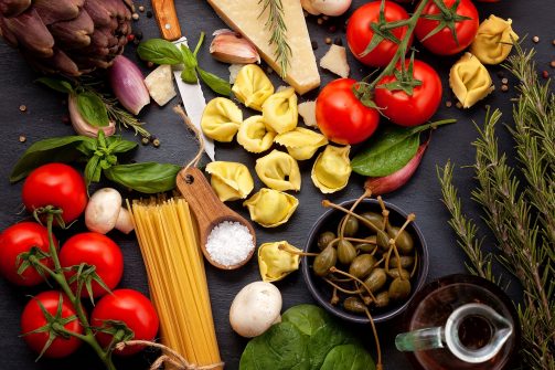 Séjour gastronomique : Ingrédients traditionels de la cuisine italienne avec légumes, huile d'olive, fromage, herbes et pâtes.